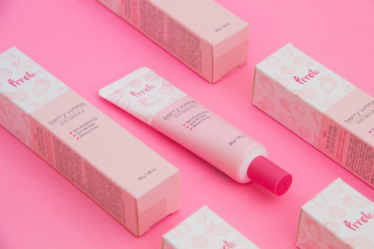 creative-03 Pink-themed flat lay of berry-white eye serum with packaging.