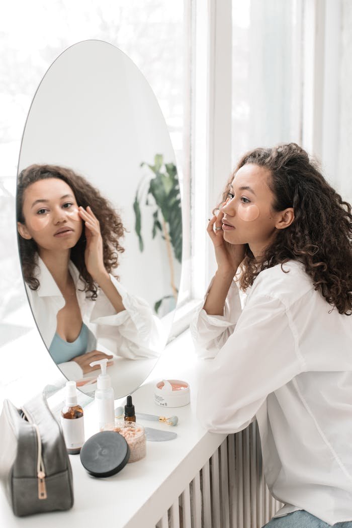 creative-02 A woman applies skincare products, sitting at a vanity with a mirror in a bright room.