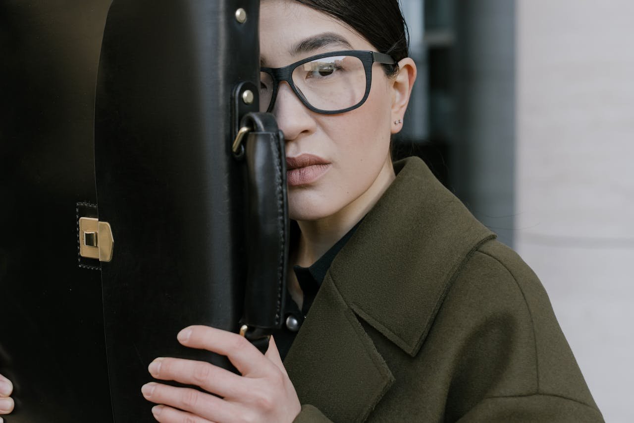 Serious Asian businesswoman holding a briefcase outdoors on a workday.